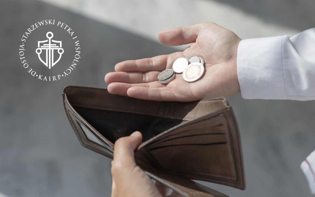 Pusta portmonetka i kilka monet w dłoni – symbol trudności finansowych po spłacie kredytu CHF.