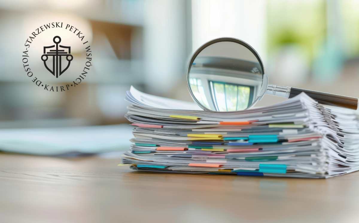 Stos uporządkowanych dokumentów z kolorowymi zakładkami i lupą na biurku.