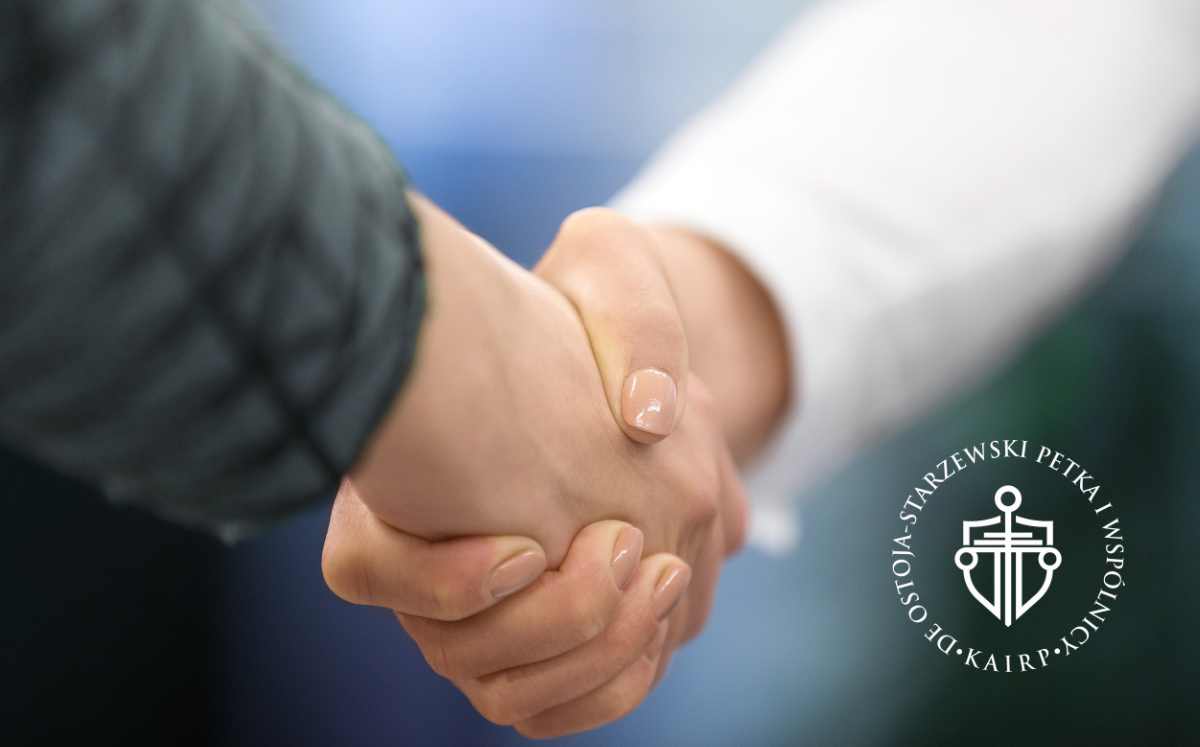 Uścisk dłoni między klientem a prawnikiem, symbolizujący zawarcie umowy i zaufanie, na dole po prawej logo kancelarii prawniczej.