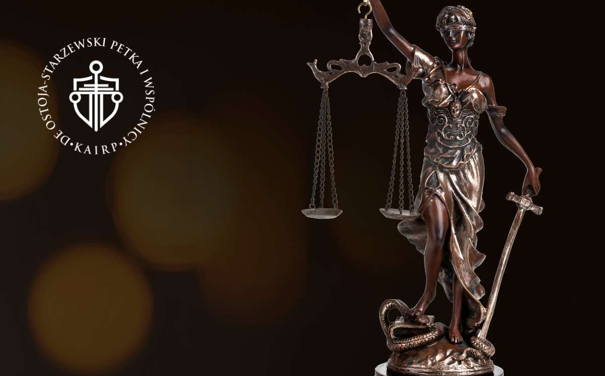Figura Temidy z wagą i mieczem w dłoniach, symbolizująca sprawiedliwość, na ciemnym tle.