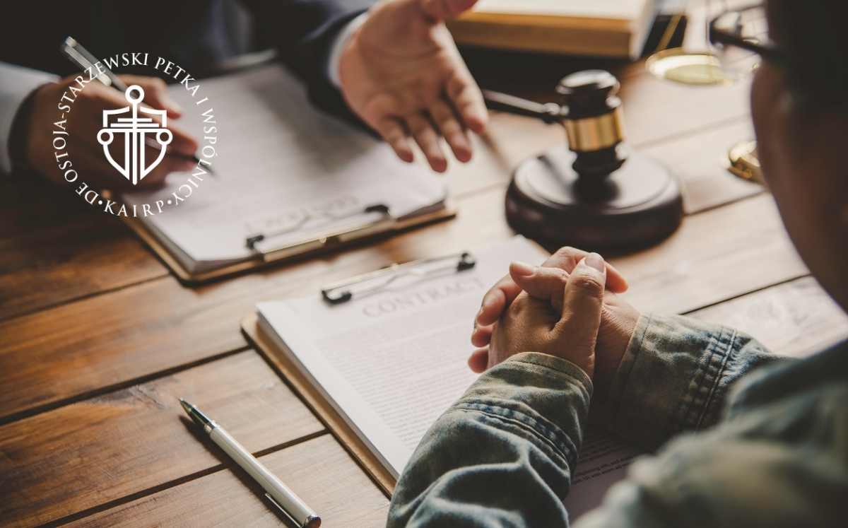 jak-zglosic-oswiadczenie-o-skd Spotkanie z prawnikiem przy biurku; na stole leżą dokumenty i młotek sędziowski, symbolizujący kwestie prawne i kontraktowe; logo kancelarii De Ostoja-Starzewski Petka i Wspólnicy.