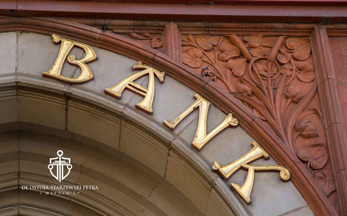 Złoty napis „BANK” nad wejściem do budynku o dekoracyjnej architekturze.