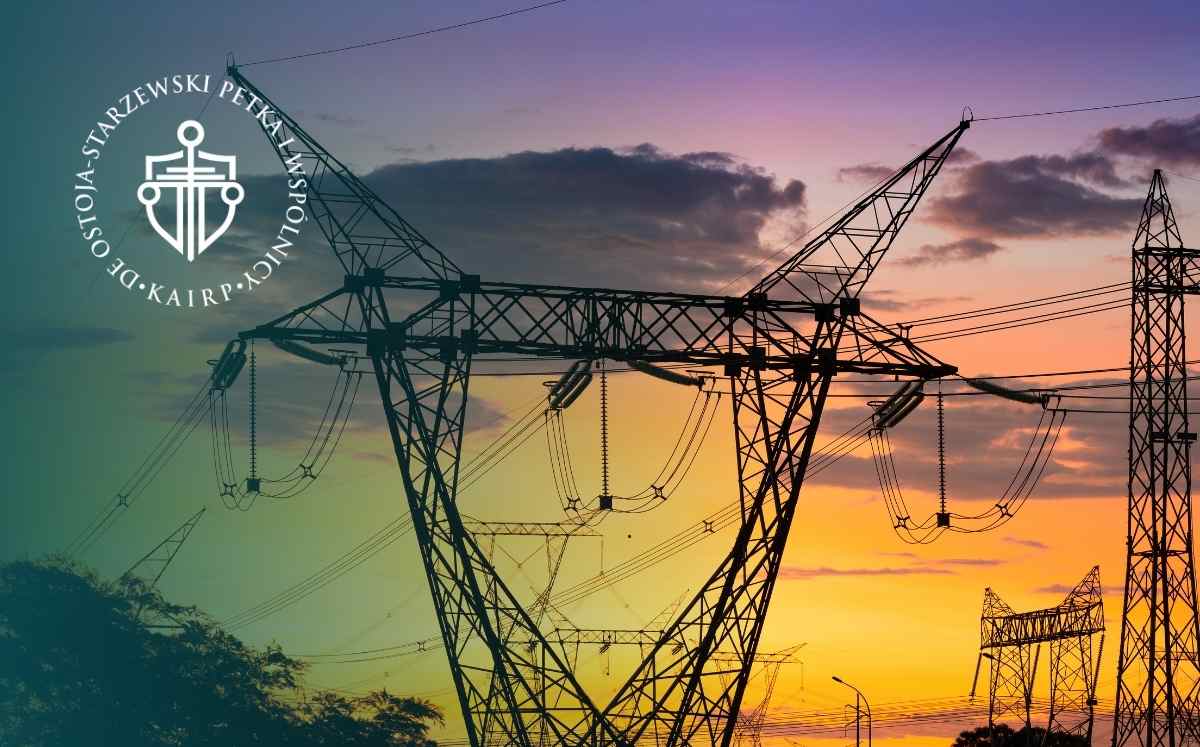 Konstrukcje słupów przesyłowych z przewodami energetycznymi na tle kolorowego nieba o zmierzchu.