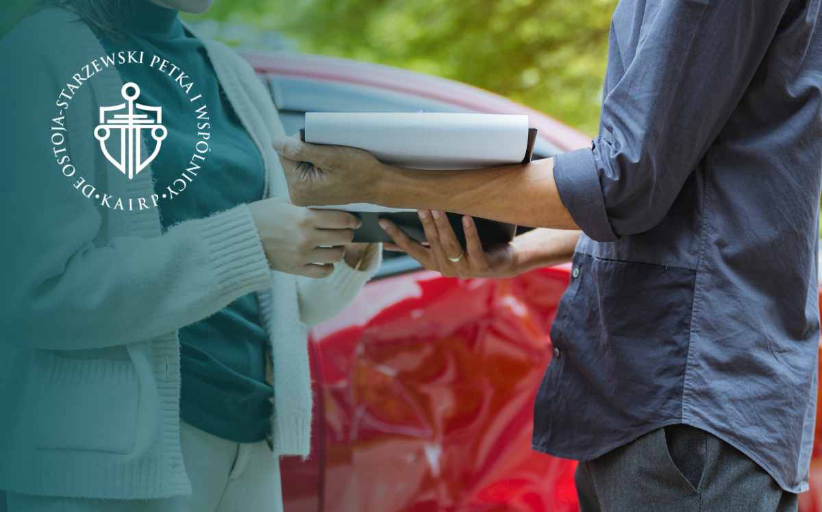 Przekazywanie dokumentów między osobami na tle uszkodzonego samochodu po wypadku