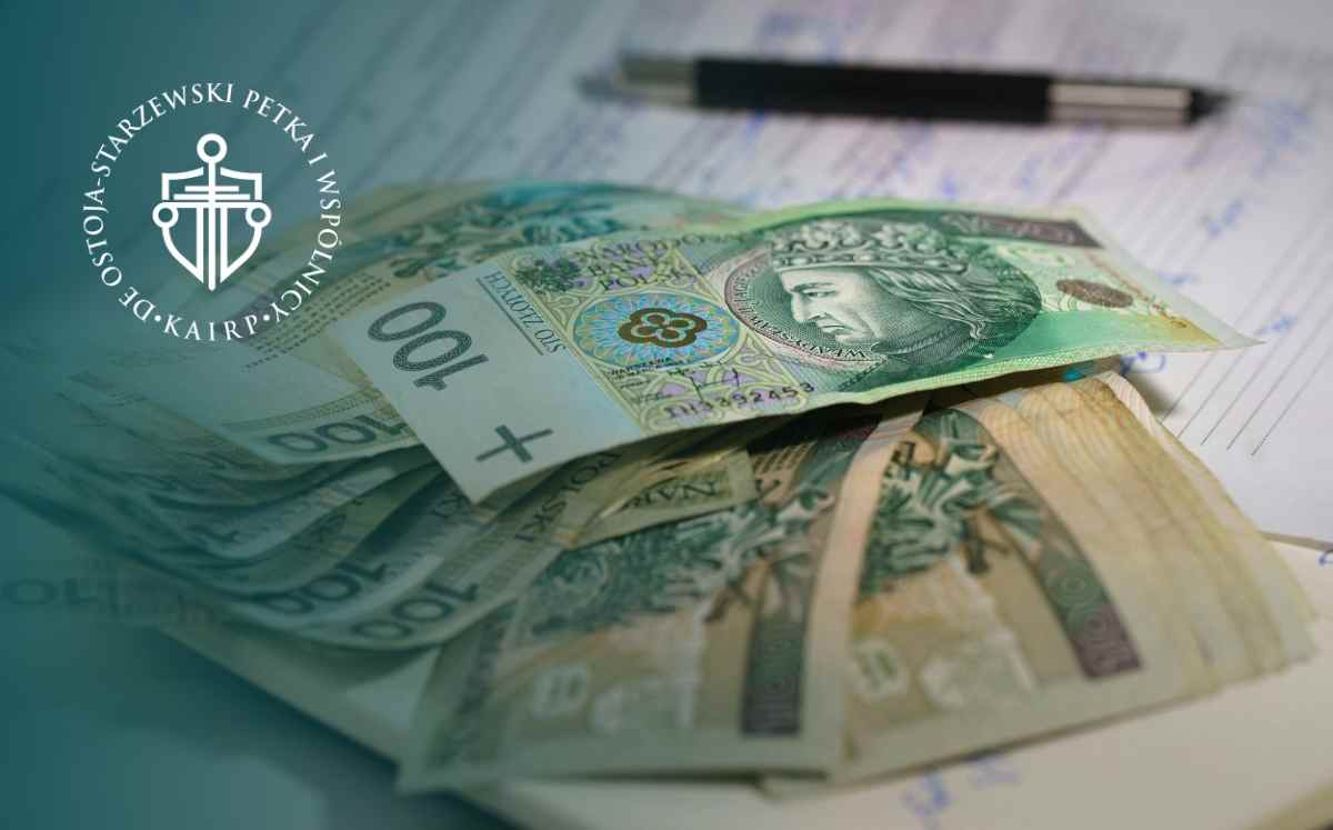 Banknoty polskich złotych o nominale 100 zł ułożone na dokumentach, w tle długopis – symbol finansów i kredytu.