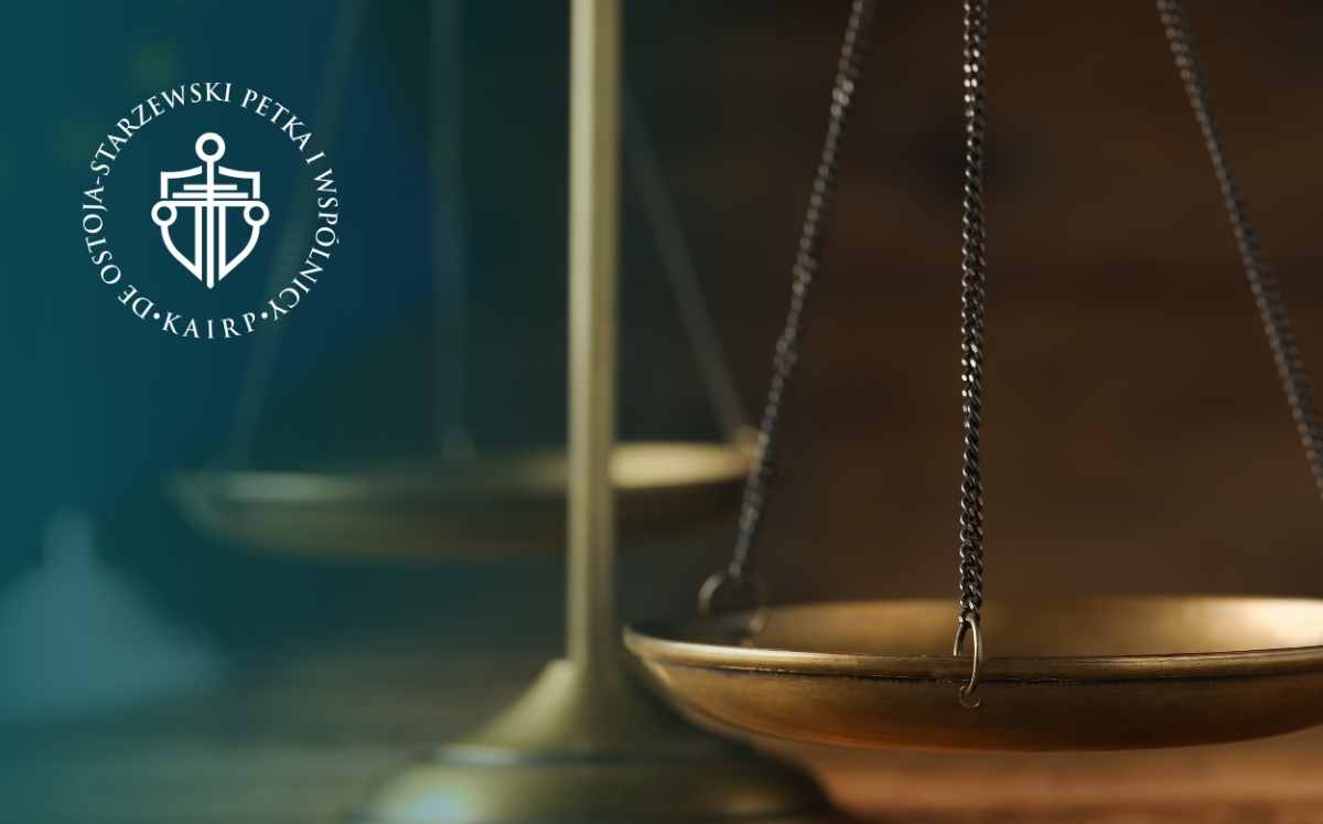 Zbliżenie na wagę sprawiedliwości na ciemnym, rozmytym tle; po lewej stronie widoczne logo kancelarii.