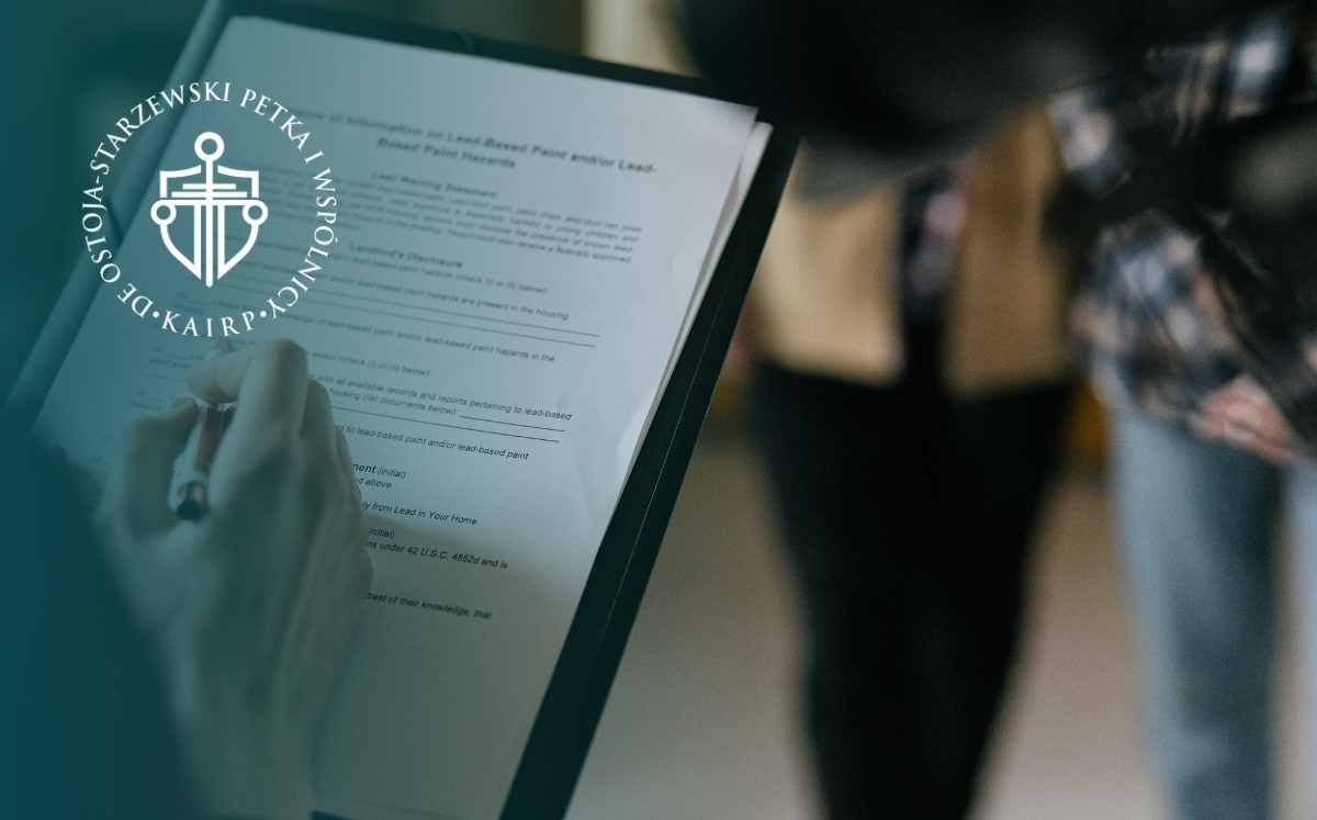 Osoba trzyma dokument i zaznacza notatki na kartce, w tle rozmyta postać, po lewej stronie widoczne logo kancelarii.