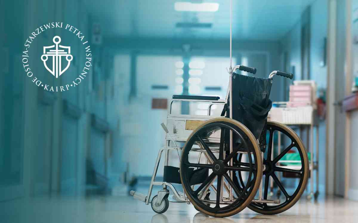 Pusty wózek inwalidzki na środku jasnego szpitalnego korytarza.