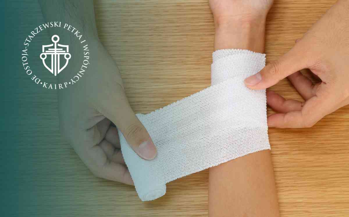 Zbliżenie na dłonie bandażujące nadgarstek na tle drewnianego blatu