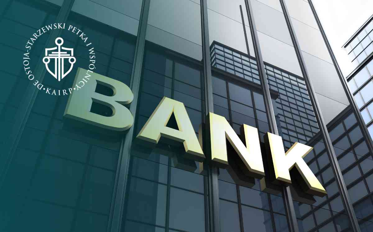 Nowoczesny, przeszklony biurowiec z dużym napisem „BANK” na fasadzie, ukazany z perspektywy dołu.