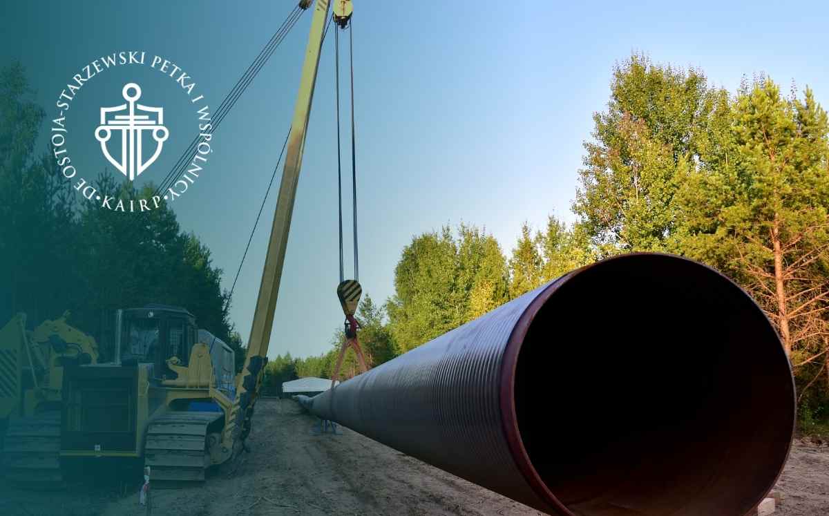 Duża rura przesyłowa transportowana przez dźwig na placu budowy w otoczeniu drzew