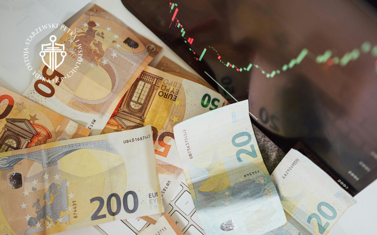 Rozrzucone banknoty euro na tle wykresu giełdowego i cenowego, sugerującego finanse lub inwestycje.