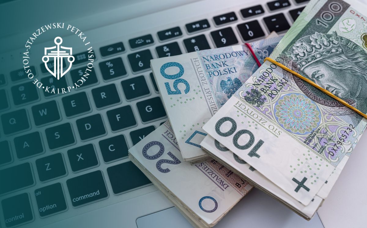 Zbliżenie na klawiaturę laptopa i leżące na niej pliki banknotów o nominałach 50, 100 i 200 zł