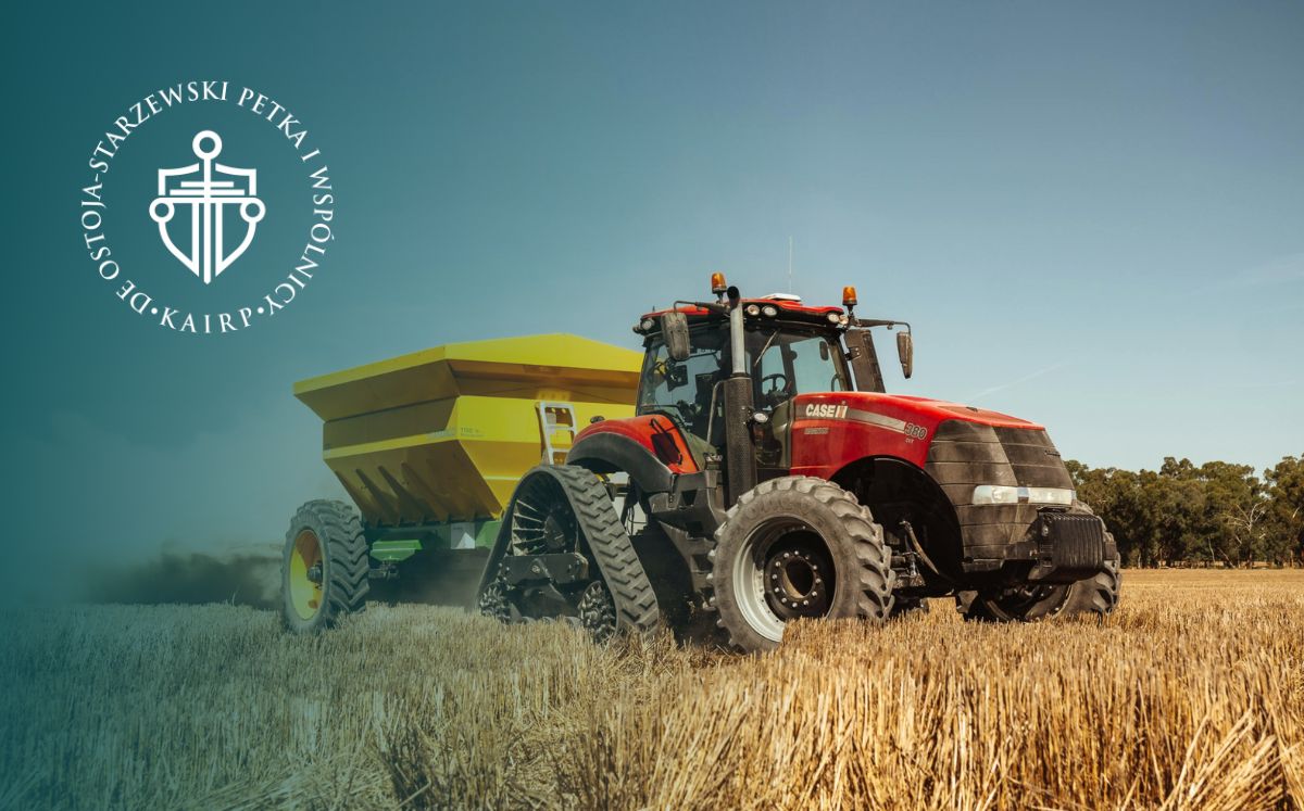 Czerwony traktor z żółtą przyczepą na tle pola