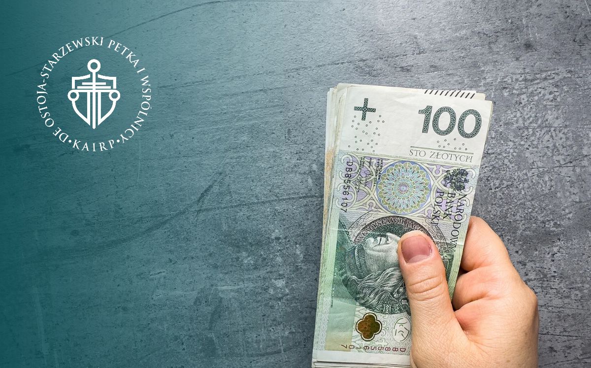 Zbliżenie na dłoń trzymającą banknoty 100 zł na szarym tle