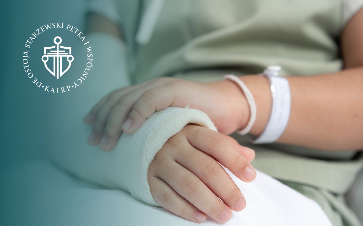 Zbliżenie na rękę w gipsie. Osoba trzyma się za nią drugą dłonią